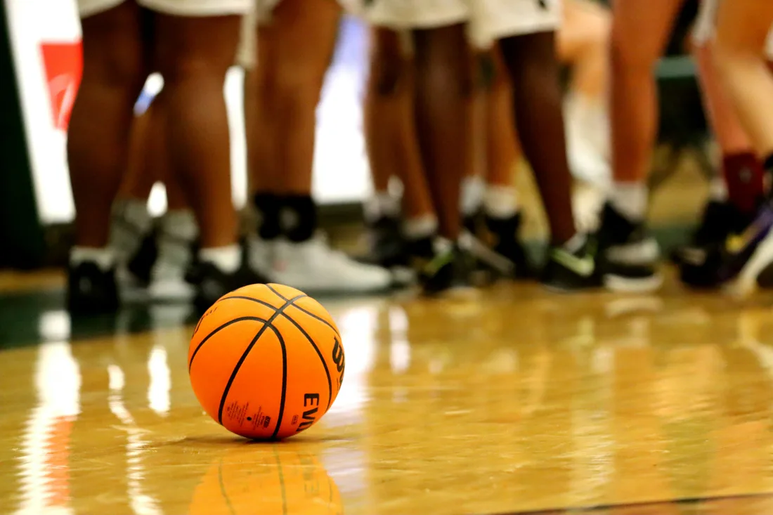 Basketball auf dem Hallenboden, dahinter eine Trainingsgruppe